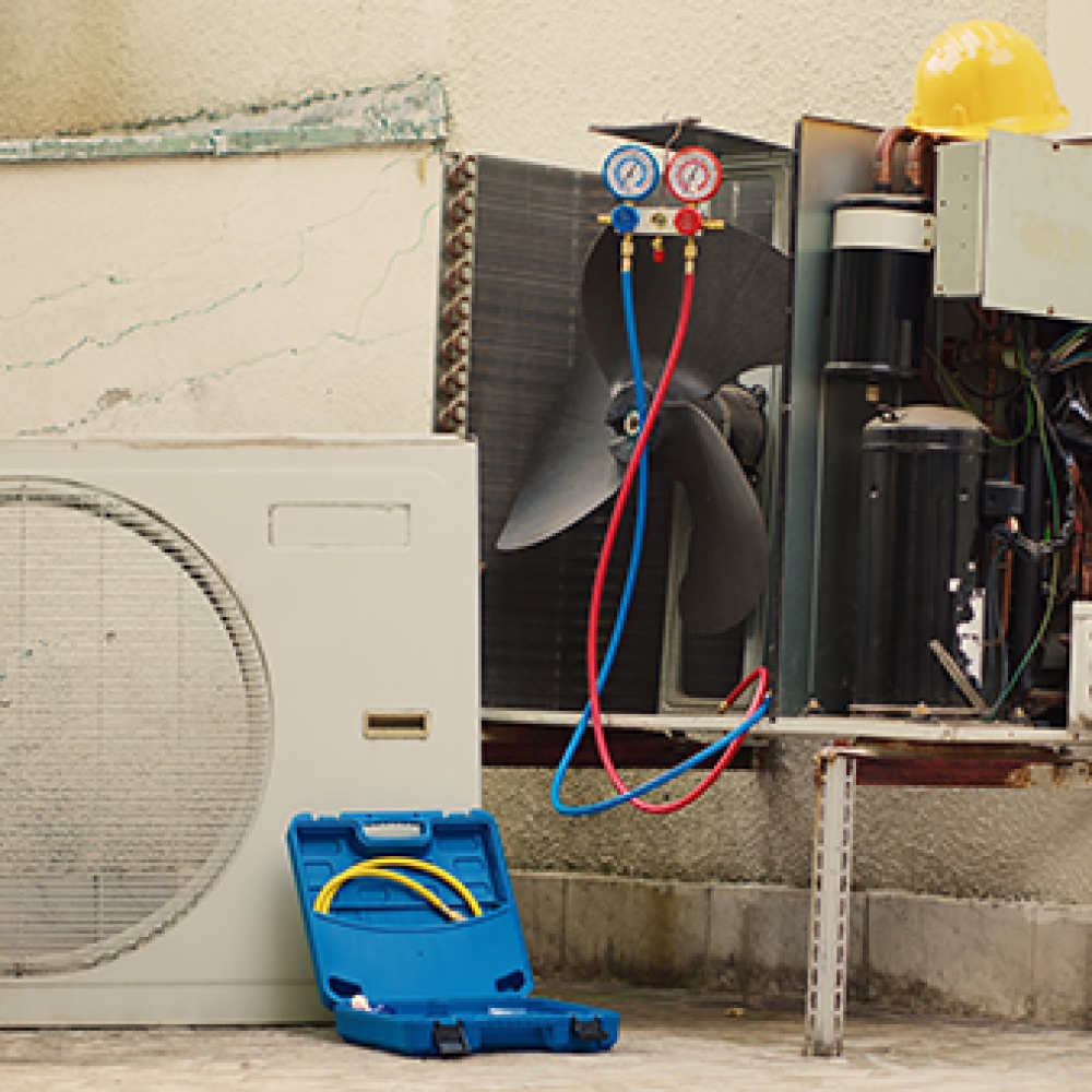 Zoom in close up shot of broken external air conditioner unit with protection cover removed in need of repair, with damaged electric internal components and faulty wiring