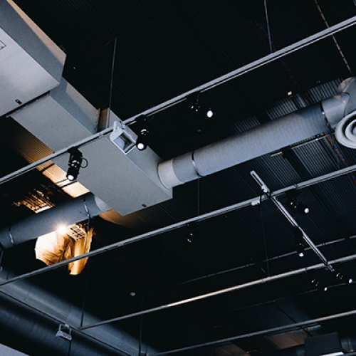 A low angle shot of a metal black ceiling with white ventilation pipes